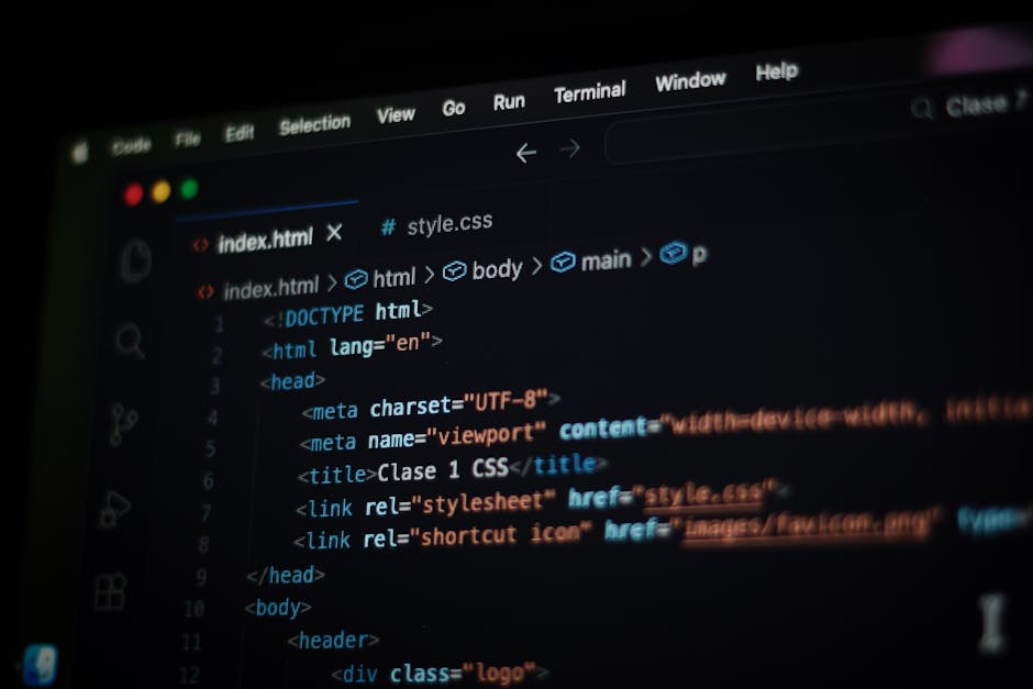Photograph of a computer screen displaying lines of colourful programming code with syntax highlighting, including various keywords, functions, and variables, set against a dark background. The monito